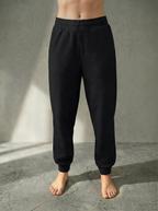 Front iew of the Deryn women’s luxury jogger pants Black colour, by BOU Clothing shown on a model standing barefoot against a stone grey  backdrop.