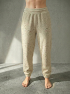 Front view of the Deryn women’s luxury jogger pants beige with red fleck  colour, by BOU Clothing shown on a model standing barefoot against a stone grey  backdrop.