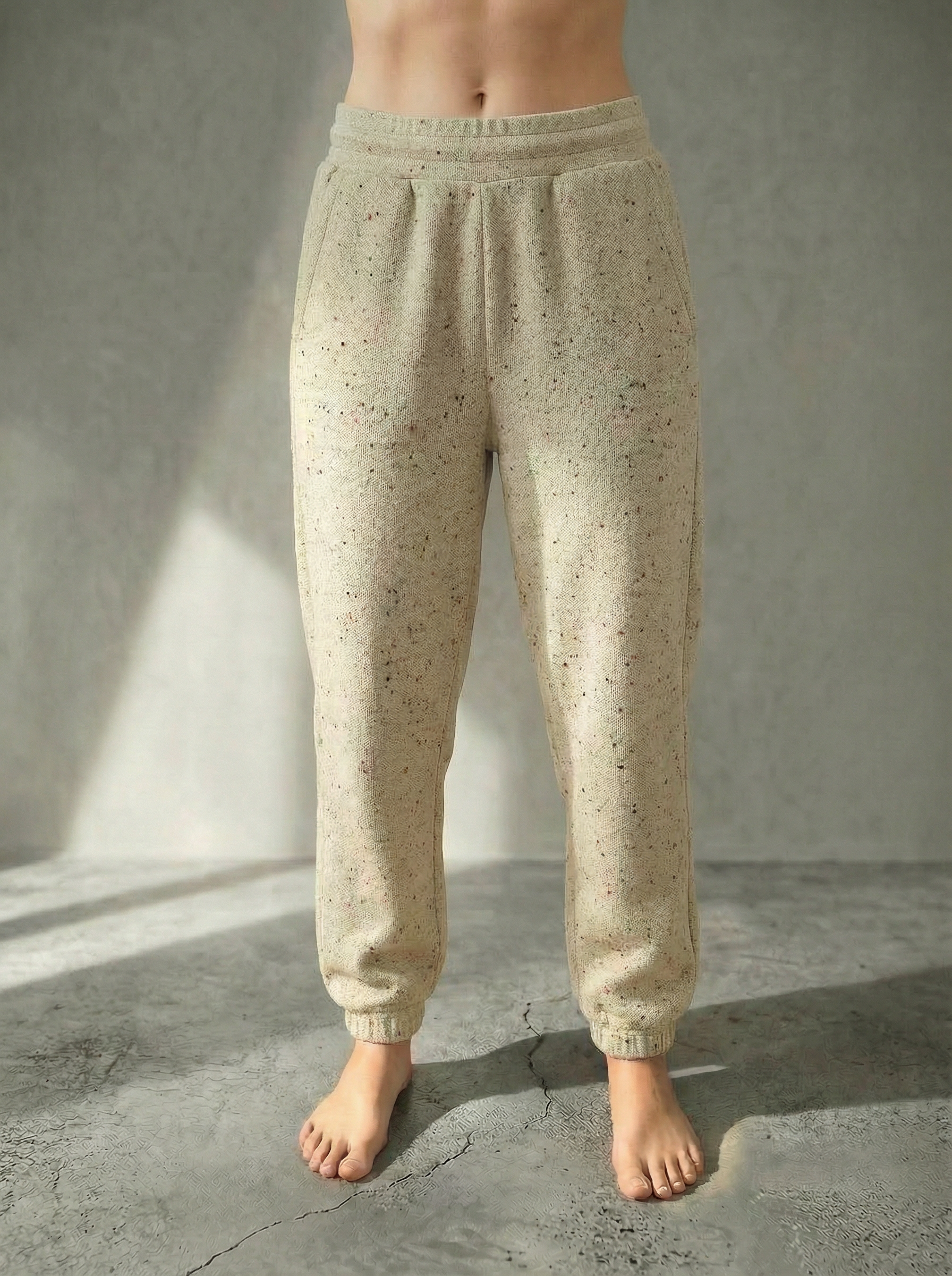 Front view of the Deryn women’s luxury jogger pants beige with red fleck  colour, by BOU Clothing shown on a model standing barefoot against a stone grey  backdrop.