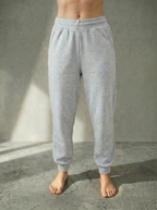 Front view of the Deryn Jogger women’s luxury jogger pants by BOU Clothing in grey, shown on a model standing barefoot against a stone gray backdrop.