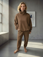 Model wearing Bou Clothing’s Tan Deryn luxury hoodie and matching joggers, in a softly lit modern interior, showcasing a relaxed fit, premium fabric, and minimalist neutral style.