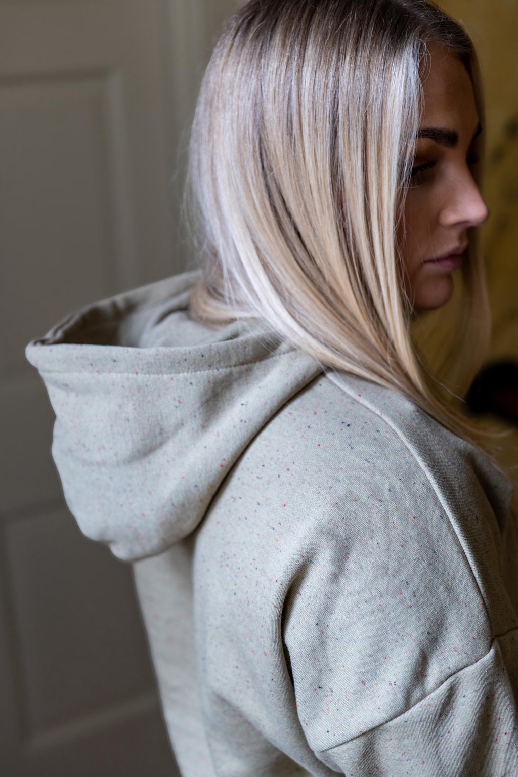 Woman wearing a light gray hoodie with a blurred background