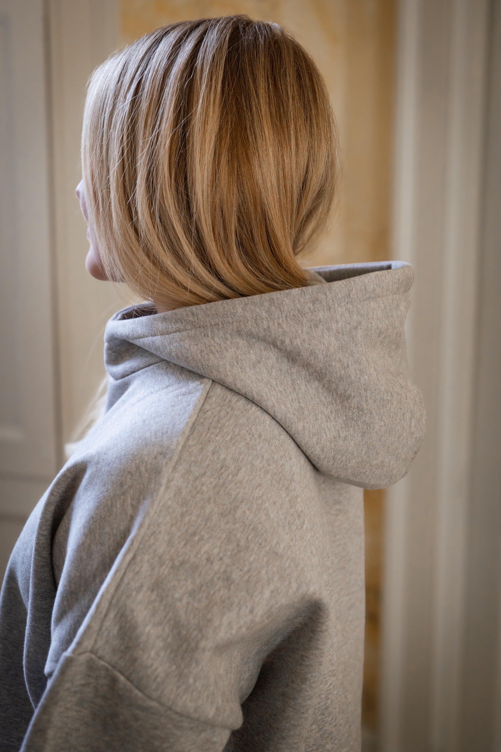 Person wearing a grey hoodie with a neutral background
