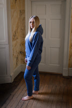 Person wearing a blue tracksuit standing in a room with marble walls and wooden floor.