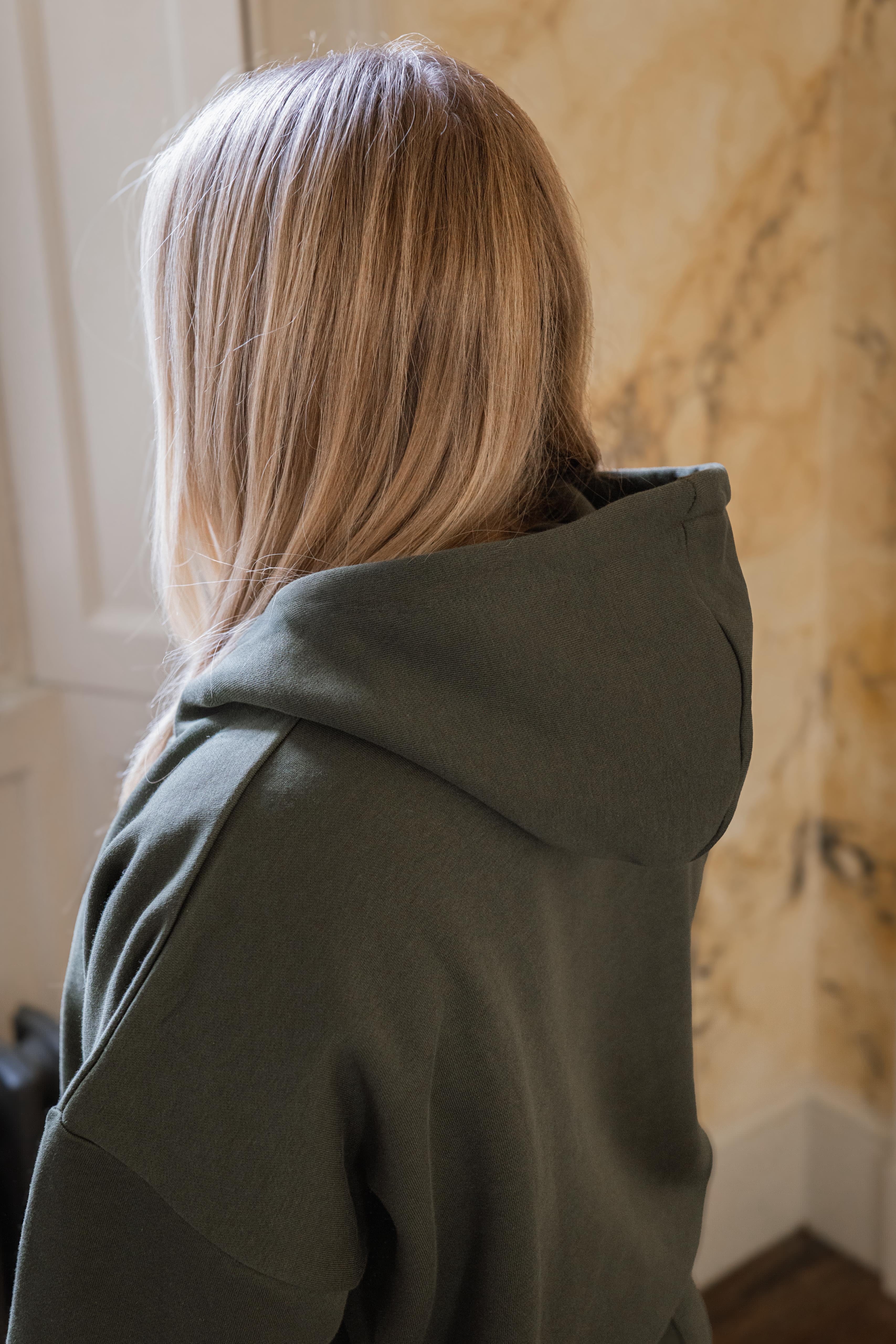 Person wearing a green hoodie with a neutral background
