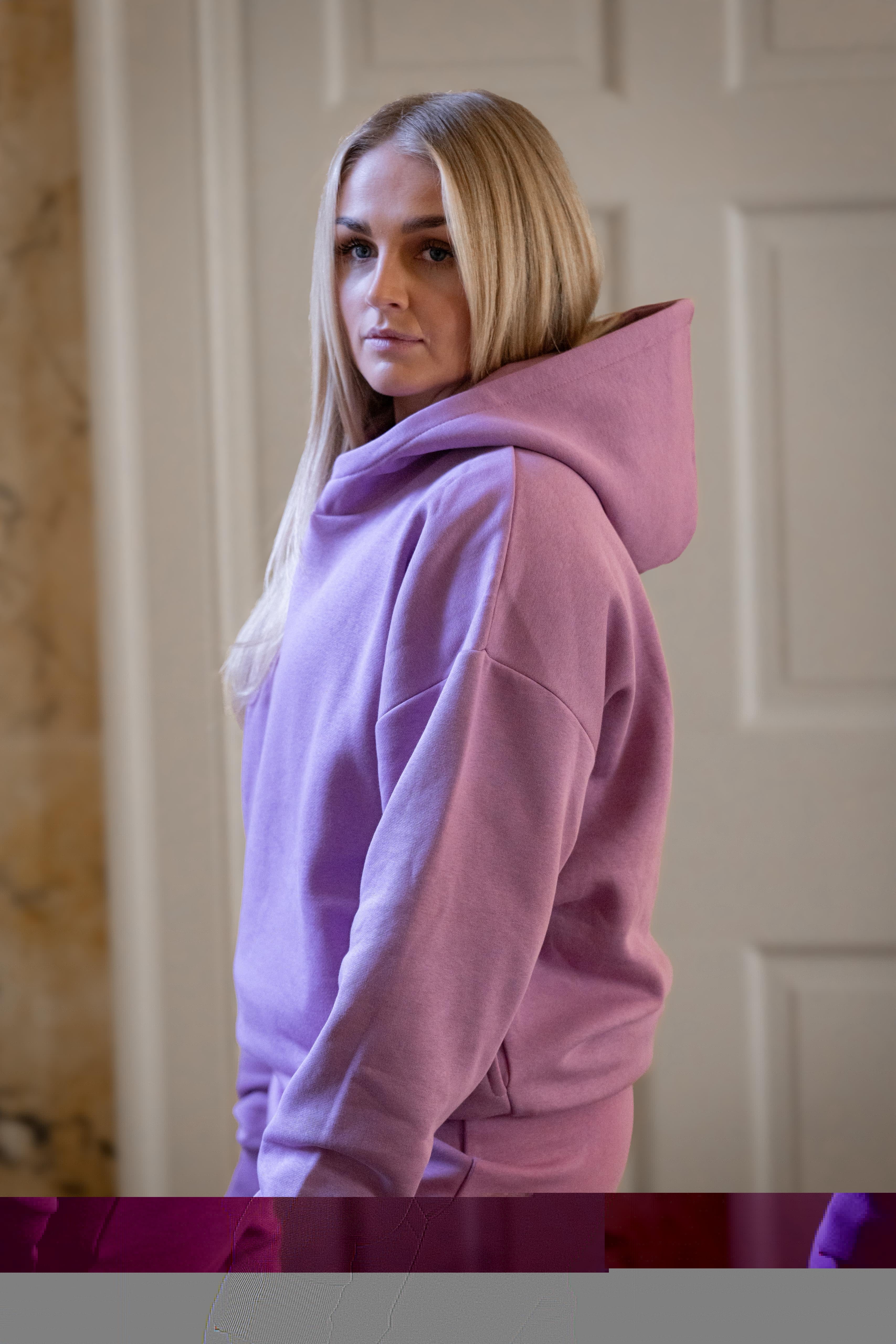 Person wearing a pink hoodie in a neutral setting